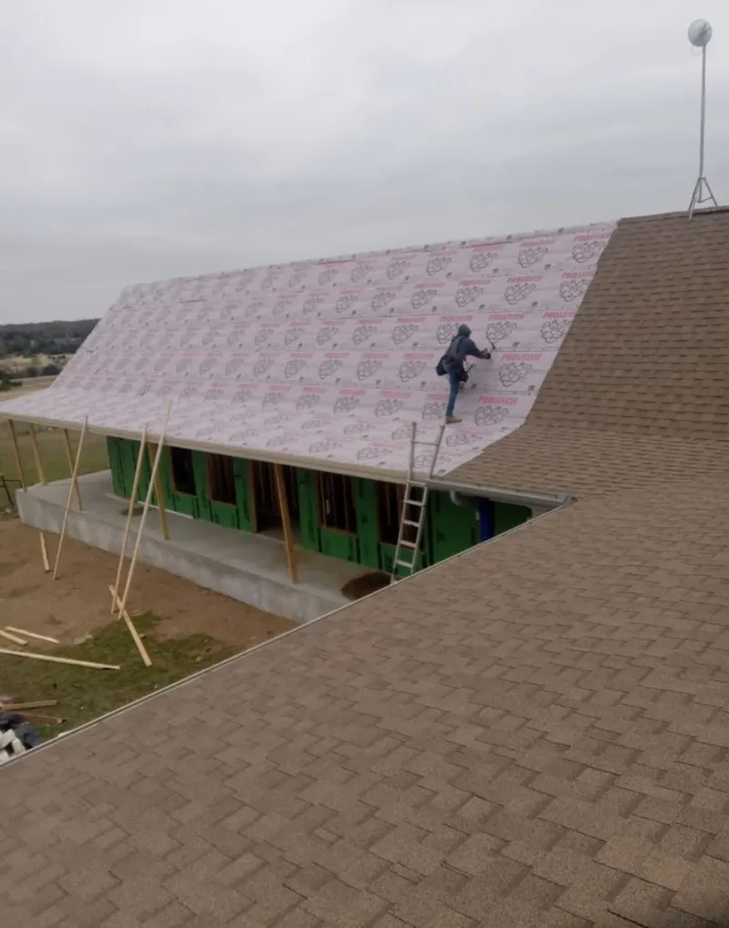 Worker preparing underlayment for a metal roof installation in Rosemont